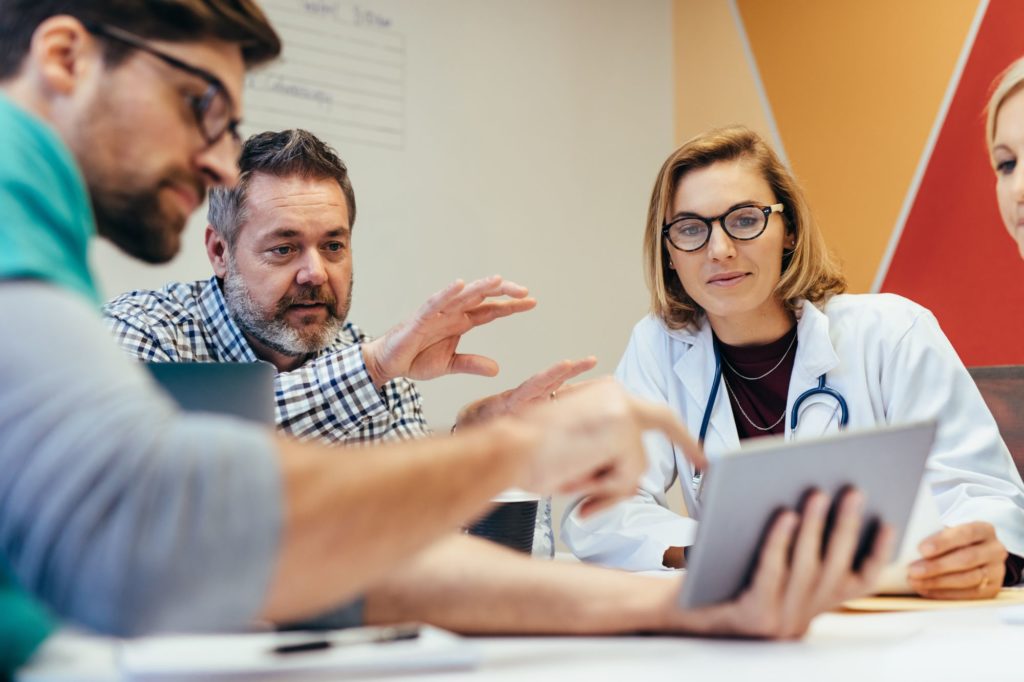 Medical staff and other professionals looking at tablet